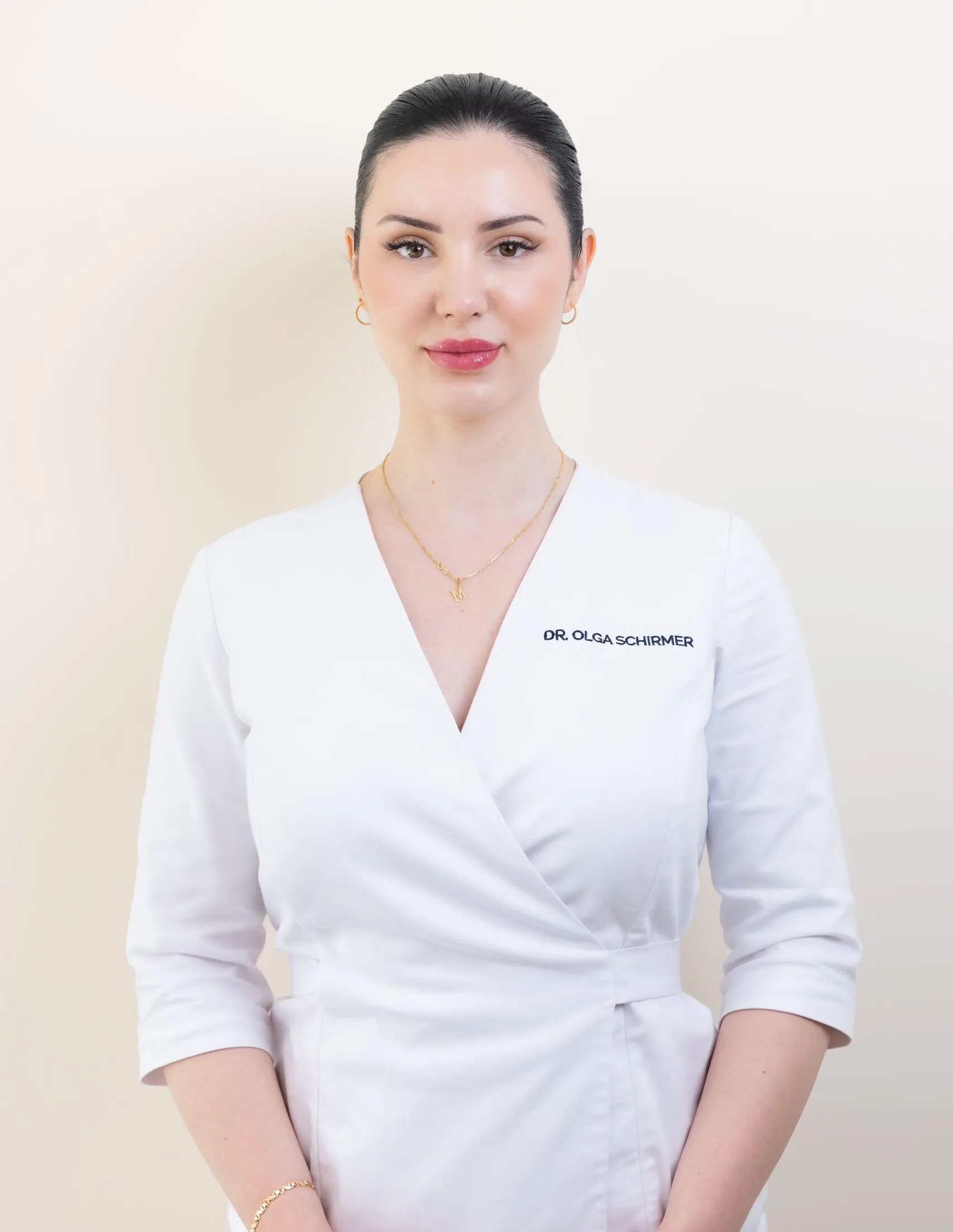 Dr. Olga Schirmer in a clinic coat, welcoming clients to her aesthetic practice